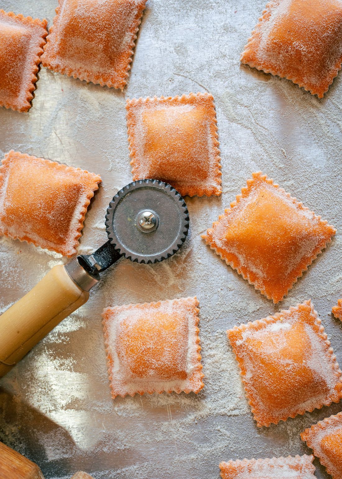 Raviolones recién cortados sobre la mesa enharinada